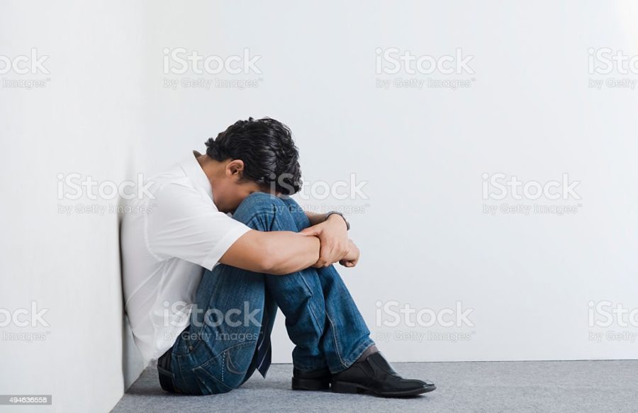 University student sitting in the corner with head down
